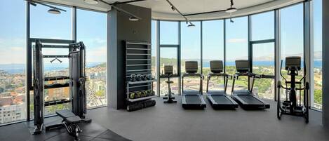 A gym with large windows, treadmills, weight machines, and dumbbells.