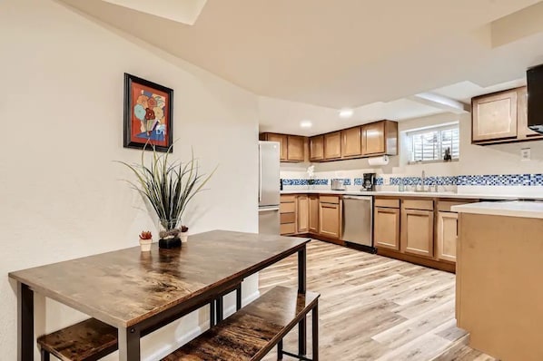 Cocina moderna con armarios de madera, salpicadero azulejado y comedor con mesa y banco de madera.