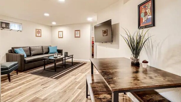 A modern living room with a sofa, coffee table, and a TV mounted on the wall. - Sloans Lake Getaway Near Broncos & Downtown Denver (Lakewood)