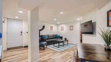 A modern living room with a sofa, coffee table, and a TV mounted on the wall.