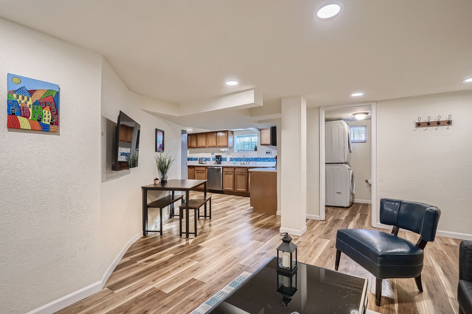 A modern kitchen with wooden cabinets, a dining area with a table and chairs, and a black leather chair.