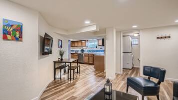 A modern kitchen with wooden cabinets, a dining area with a table and chairs, and a black leather chair.