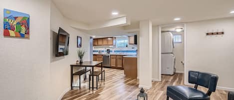 A modern kitchen with wooden cabinets, a dining area with a table and chairs, and a black leather chair.