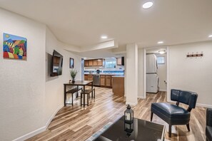 A modern kitchen with wooden cabinets, a dining area with a table and chairs, and a black leather chair.