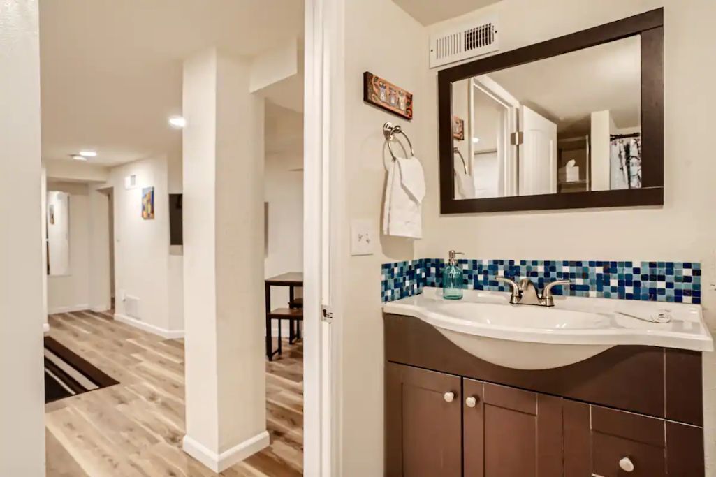 A bathroom with a large mirror, a sink, and a tiled backsplash.