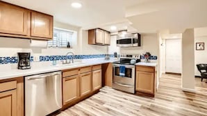 A modern kitchen with wooden cabinets, a stainless steel dishwasher, a microwave, and an oven. - Sloans Lake Getaway Near Broncos & Downtown Denver (Lakewood)
