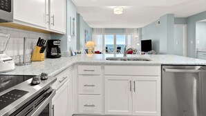 Una cucina moderna con mobili bianchi, elettrodomestici in acciaio inossidabile e un'ampia finestra con vista.