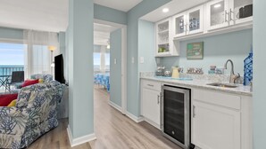 Una cucina moderna con mobili bianchi, lavastoviglie integrata e un piano di lavoro con diversi oggetti da cucina.