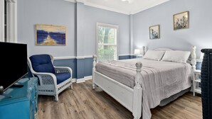 A bedroom with a bed, a chair, a desk, and a television.