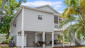 A two-story house with a balcony, a covered porch, and a small outdoor seating area.