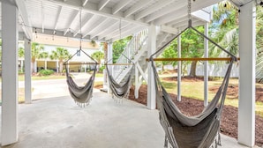 A covered outdoor area with two hammocks suspended from the ceiling, a concrete floor, and a white railing structure.