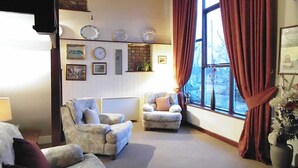 A living room with two armchairs, a sofa, a fireplace, and a large window with curtains. - 3 bedroom accommodation in Burscough, near Southport (Burscough, near Southport)