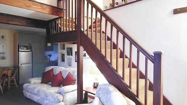 A living room with a staircase, a dining area, and a kitchen with a refrigerator. - 3 bedroom accommodation in Burscough, near Southport (Burscough, near Southport)