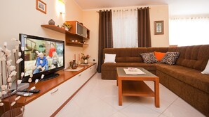 A living room with a TV, sofa, coffee table, and decorative items. - Modern flat with large terrace (Baska)