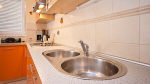 A kitchen with two stainless steel sinks, a coffee maker, and a window with blinds. - Modern flat with large terrace (Baska)