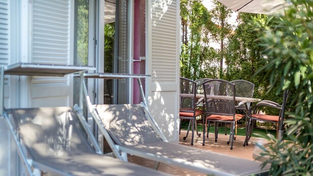 A patio with outdoor furniture, including a table and chairs, and a covered area with a bench. - Modern flat with large terrace (Baska)