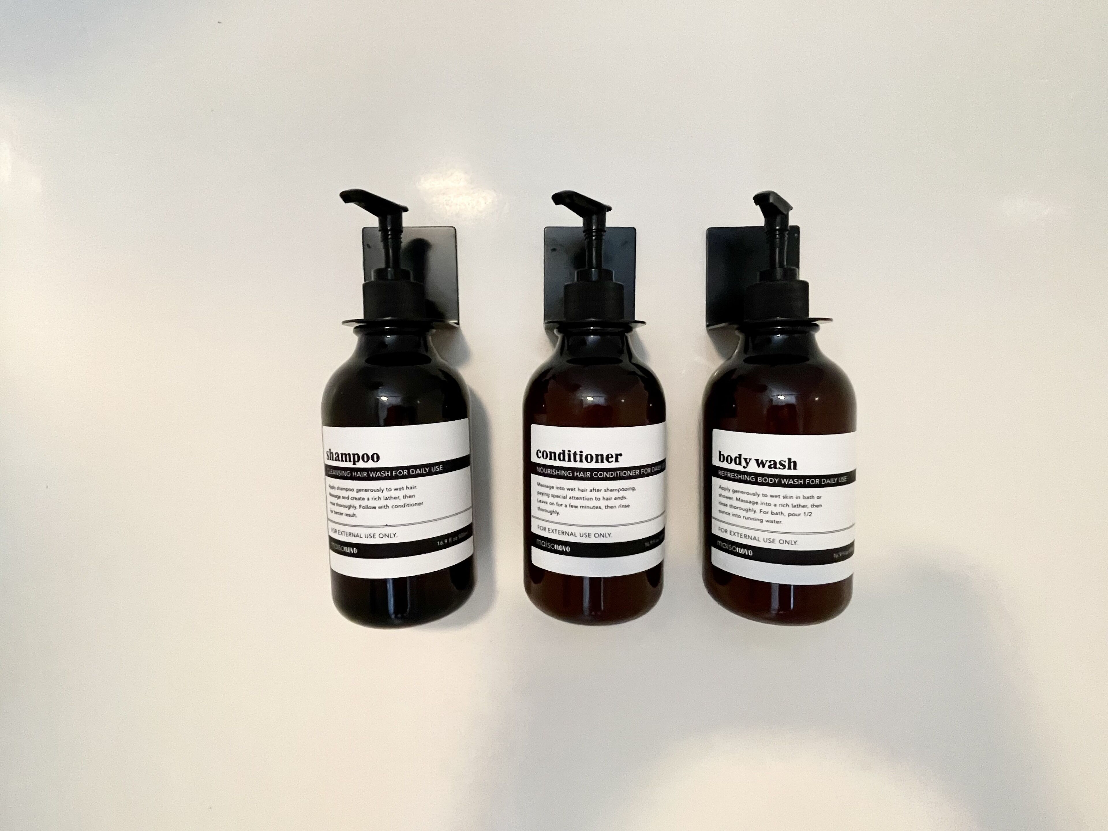 Three bottles of hair care products on a plain surface.