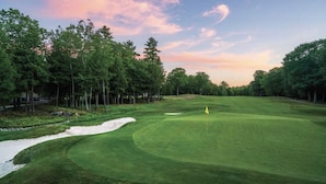Un parcours de golf avec un gazon bien entretenu, des bunkers de sable et un mât de drapeau.