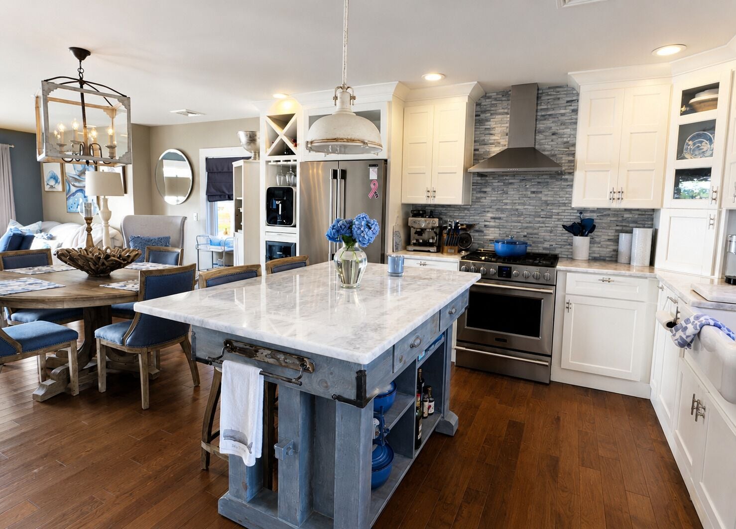 A modern kitchen with a central island, stainless steel appliances, and a stone backsplash.