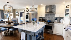 A modern kitchen with a central island, stainless steel appliances, and a stone backsplash. - Bella Vista, Luxury Waterfront Retreat Private Dock, Outdoor Living Near Newport (Portsmouth)