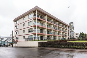 A multi-story hotel with balconies, a clock tower, and a well-maintained lawn.