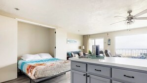 A bedroom with a bed, a desk, and a view of the beach. - Sand Dollar Haven at Seaside Beach Club Unit 306 (Seaside)