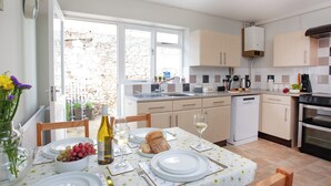 A modern kitchen with white cabinets, a built-in oven, and a dining area with a table set for two. - 2 bedroom accommodation in Dawlish (Dawlish)