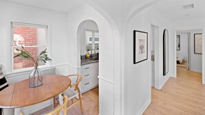 A modern kitchen with white cabinetry, a granite countertop, and a window with a red brick wall view. - Classic Balboa Cottage, Newly Updated with A/C! (Newport Beach)