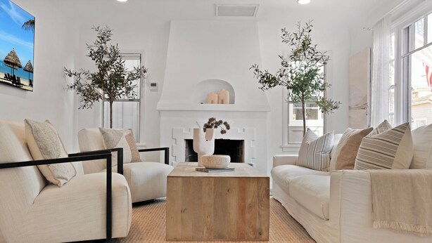 A modern living room with a fireplace, two sofas, a coffee table, and large windows. - Classic Balboa Cottage, Newly Updated with A/C! (Newport Beach)