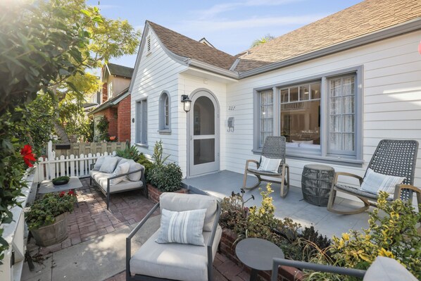 A house with a covered patio, a white exterior, and a brick chimney.
