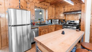 A modern kitchen with wooden cabinets, stainless steel appliances, and a wooden countertop.