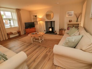 A cozy living room with a sofa, a coffee table, a fireplace, and a television.