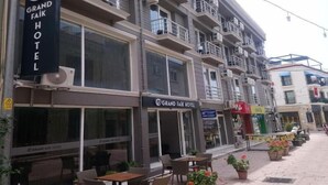 Een hotel met meerdere verdiepingen, balkons, zitplaatsen buiten en plantenbakken.