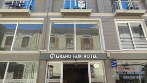 Een meerlaags hotel met balkons, airconditioners en een bord met de naam Grand Faik Hotel.