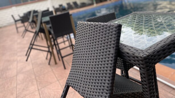 A poolside area with wicker chairs and a glass-top table. - Novatel Hotel (Lekki)