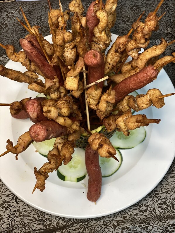 Un plato de brochetas de carne con rodajas de pepino.