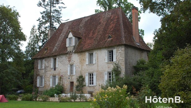 A stone building with multiple windows and a red roof, surrounded by greenery. - Le château du Fraysseix à Roziers-Saint-Georges (Roziers-Saint-Georges)