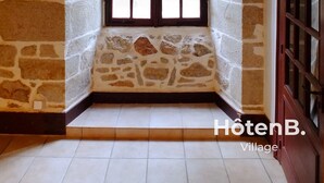 A corner room with a stone wall, a wooden door, and a window with a view of greenery. - Le château du Fraysseix à Roziers-Saint-Georges (Roziers-Saint-Georges)