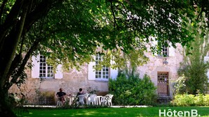 A stone building with a garden and outdoor seating area. - Le château du Fraysseix à Roziers-Saint-Georges (Roziers-Saint-Georges)