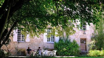 Un bâtiment en pierre doté d’un jardin et d’un espace extérieur aménagé pour s’asseoir.