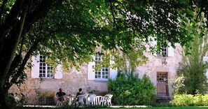 Un bâtiment en pierre doté d’un jardin et d’un espace extérieur aménagé pour s’asseoir.