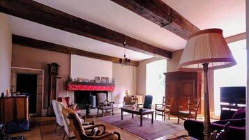 A spacious living room with wooden floors, a fireplace, and a television.