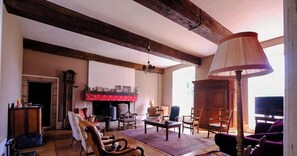 Un salon spacieux doté de parquets en bois, d’une cheminée et d’un téléviseur.