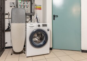 A white Samsung washing machine in a room with a teal door and a control panel with various switches and indicators.