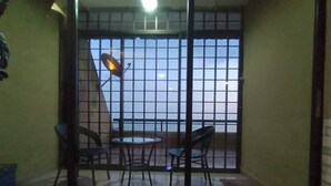 Un balcón con puerta de cristal, dos sillas, una mesita redonda y una antena parabólica.