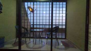 A balcony with a glass door, two chairs, a small round table, and a satellite dish.