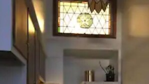 Une petite cuisine équipée d’une cuisinière à gaz, d’un réfrigérateur et d’une fenêtre ornée d’un motif décoratif.