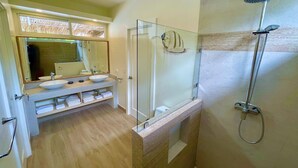 A bathroom with a glass-enclosed shower, a large mirror, and a vanity with a bowl sink and multiple shelves for towels. - Amazing new modern house close to the beach (Potrero)