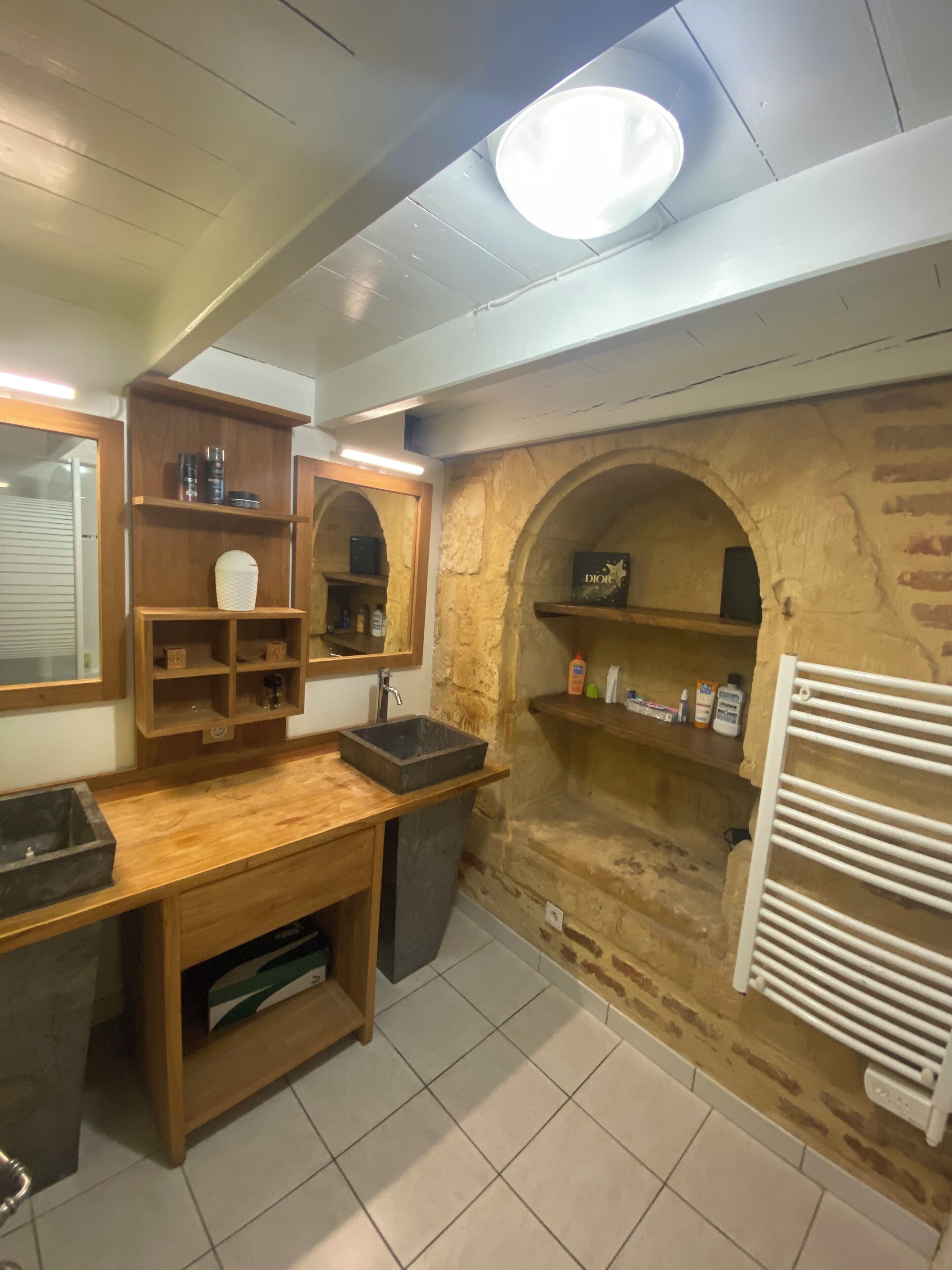 Ein Badezimmer mit einem Holzkosmetikschrank, einem Waschbecken, einem Spiegel und einem Handtuchhalter.