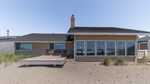 Una moderna casa sulla spiaggia con un'ampia terrazza, facciata in mattoni e grandi vetrate.